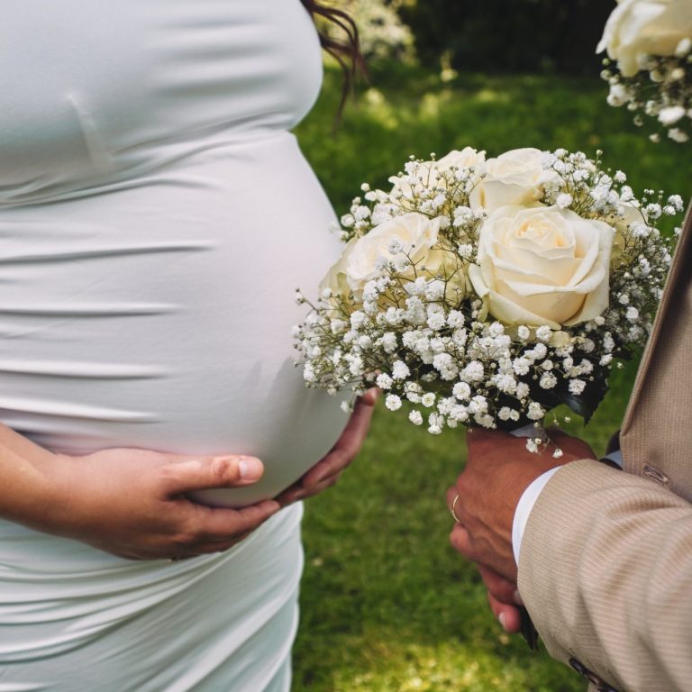 Hochzeitsfoto von schwangere Braut mit Fokus auf Babybauch