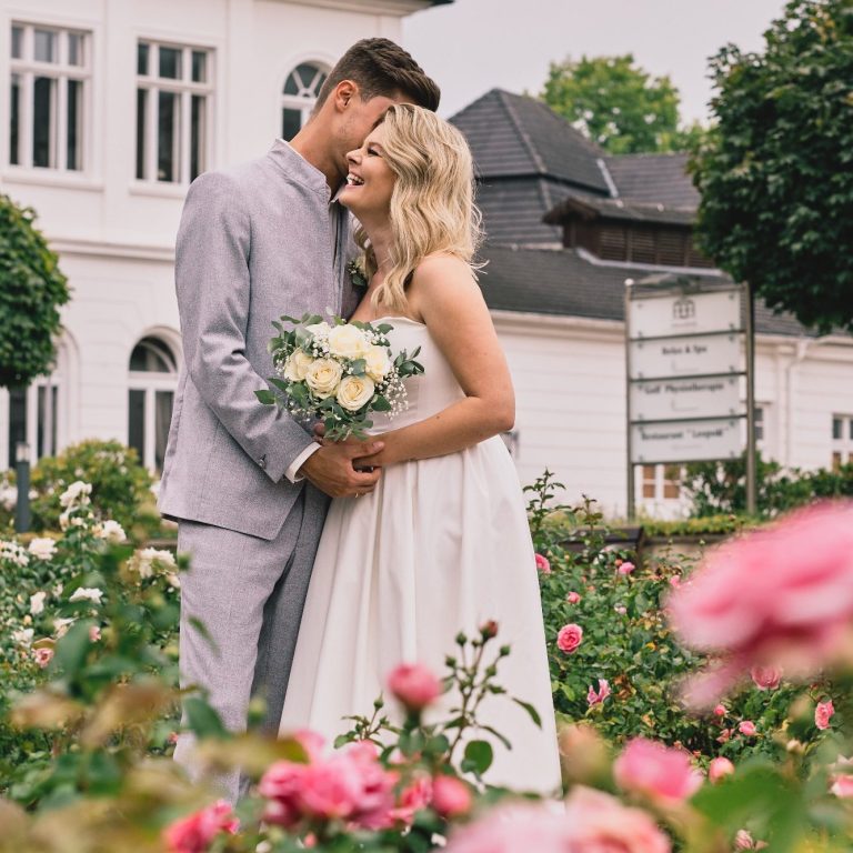 Foto von Hochzeitspaar mit vielen Blumen in einem Park in Herford