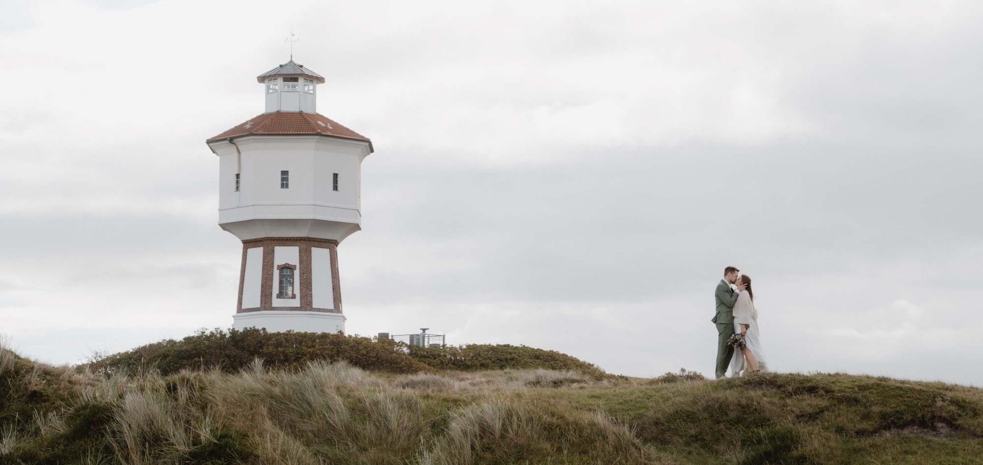 Brautpaar vor dem Wasserturm Langeoog Brautpaar vor dem Wasserturm auf Langeoog während einer authentischen Hochzeitsreportage