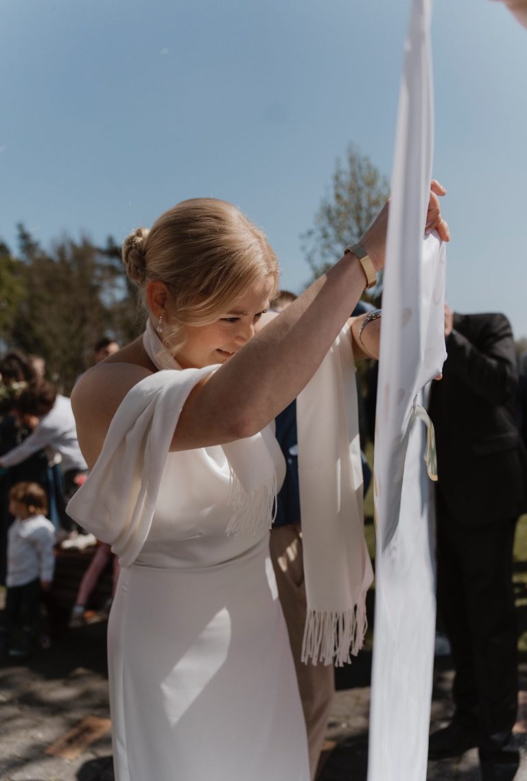 Braut beim Durchschneiden des Bettlakens Braut schneidet nach der standesamtlichen Trauung ein Bettlaken als traditionellen Hochzeitsbrauch durch.