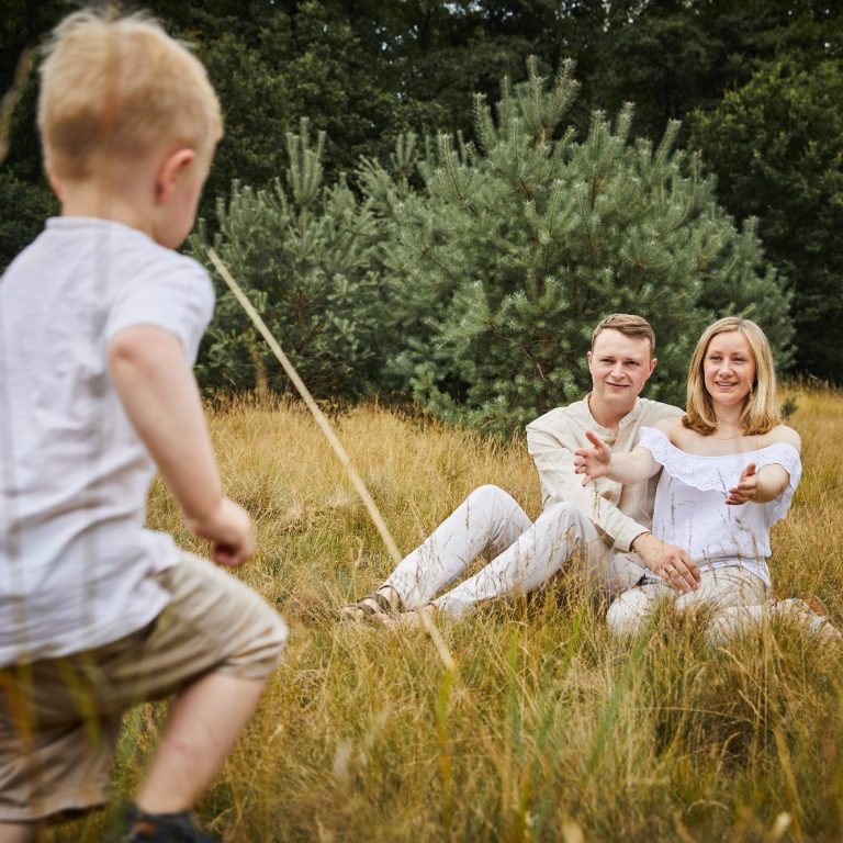 Kind läuft Eltern auf grüner Wiese entgegen